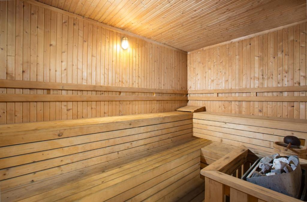 Koka saunas interjers ar koka soliņiem un apgaismojumu, radot mierīgu un relaksējošu atmosfēru. Sāls un akmeņu trauks papildina saunas pieredzi.
