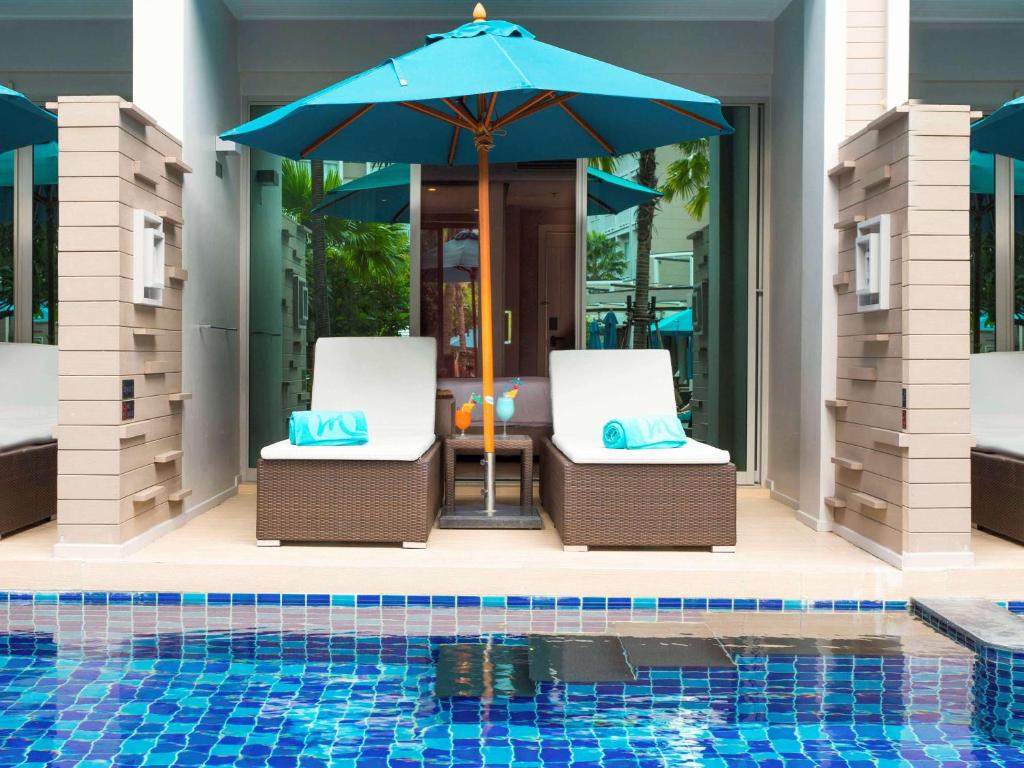 Atpūtas zona pie Grand Mercure Phuket Patong ar saules krēsliem un lietussargiem.