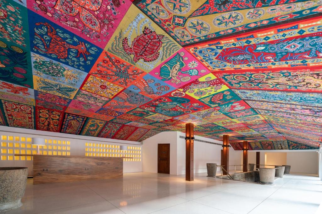 Krāsains griestu dizains ar etniskām ilustrācijām, kas rotā modernu telpu. Interjers ar koka akcentiem un minimālistisku apgaismojumu.