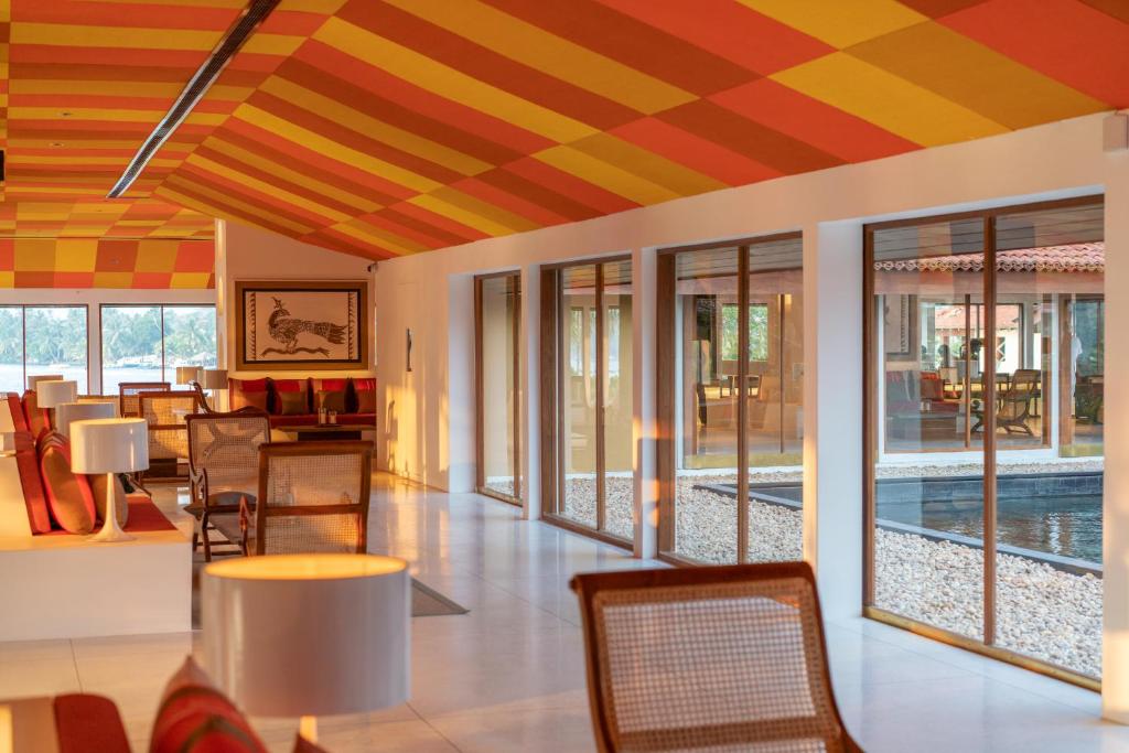 Mūsdienīgs interjers ar krāsainu griestu un plašiem logiem, kas piedāvā skatu uz dārzu. Telpa ir izgaismota ar saulrieta gaismu, radot siltu un viesmīlīgu atmosfēru.