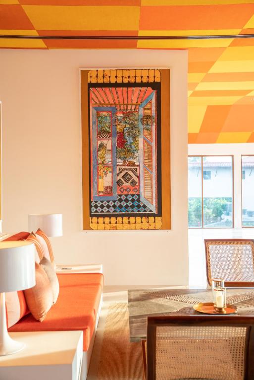 Mākslas darbs pie sienas, kas attēlo logus ar dzīvību un krāsām, piešķir dzīvotnes interjeram spilgtumu un stilu. Siltas krāsas un tekstūra rada patīkamu atmosfēru.