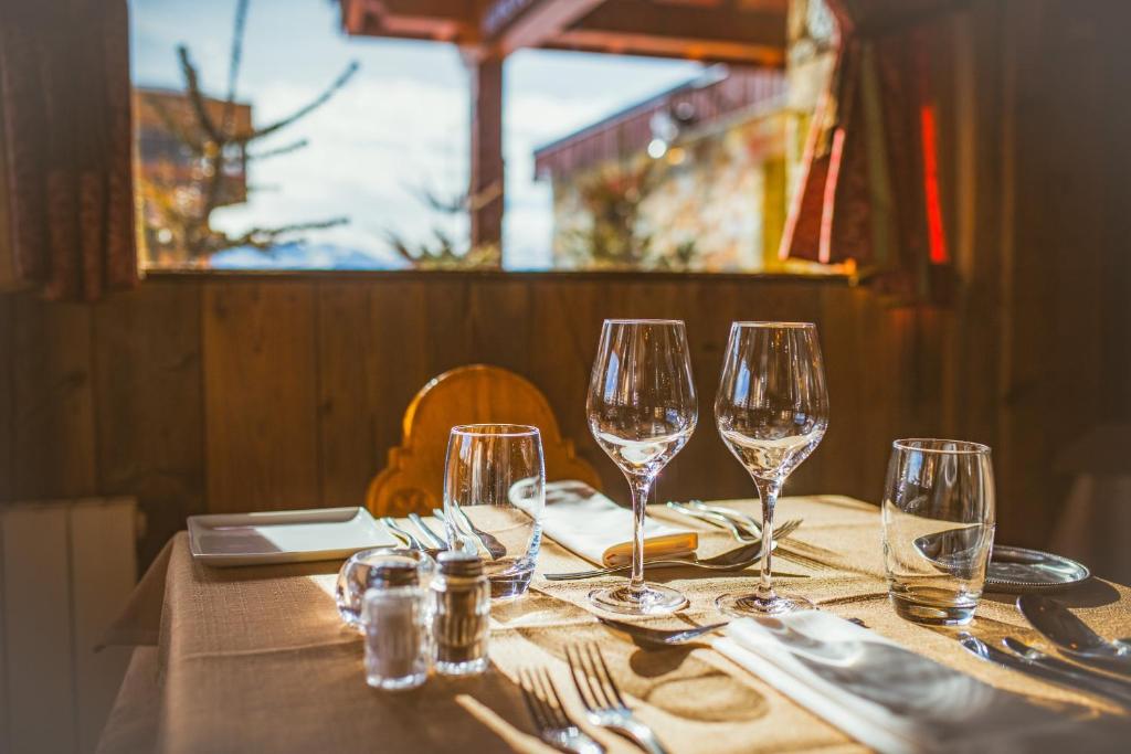 Elegantā galda klāšana ar glāzēm un galda piederumiem, kas novietota pie loga ar skatu uz dabu. Ideāla atmosfēra romantiskai vakariņai vai svinībām.