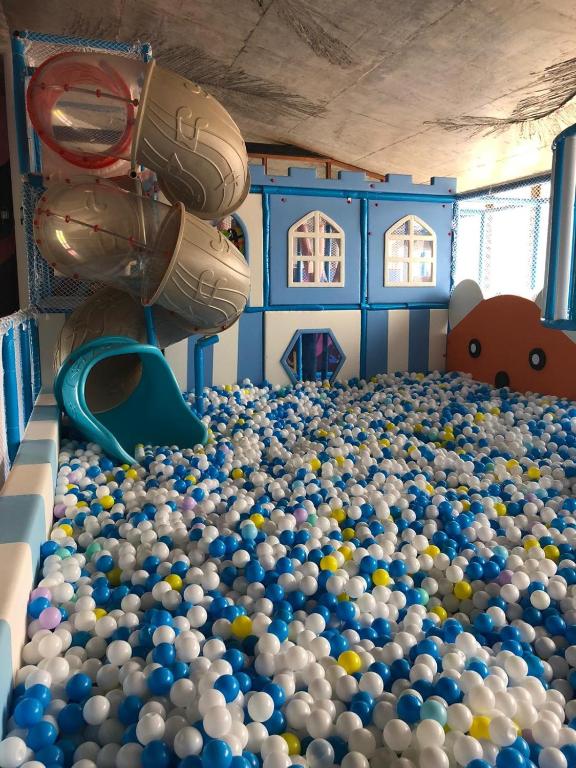 Bērnu spēļu istaba ar krāsainiem bumbiņu baseiniem, slidkalniņiem un rotaļu elementiem. Šī vide ir ideāla izklaide un prieks bērniem.