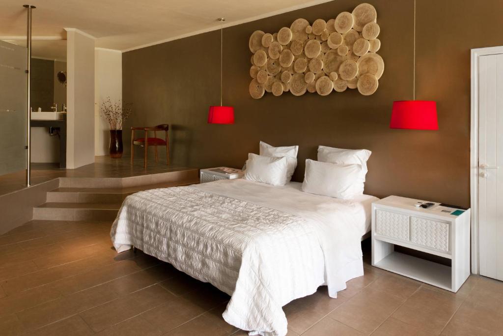 Moderns guļamistabas interjers ar divguļamo gultu, sarkaniem lampām un dekoratīvām koka plāksnēm uz sienas. Telpa ir gaiša un eleganta, radot relaksējošu atmosfēru.