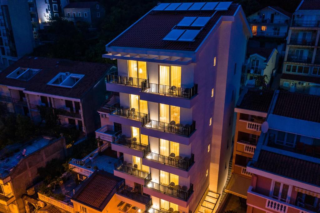 Mūsdienīga ēka ar balkoniem, apgaismota tumšā naktī, apkārt esošās struktūras un terases. Ideāla vieta atpūtai un relaksācijai.