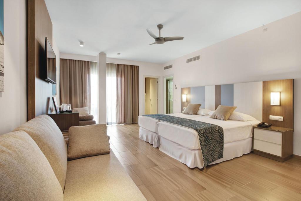 Mūsdienīgs viesnīcas numurs ar divām gultām, dīvānu un televizoru, apgaismojums radot komfortablu atmosfēru. Lieli logi nodrošina dabisko apgaismojumu un piekļuvi balkonam.