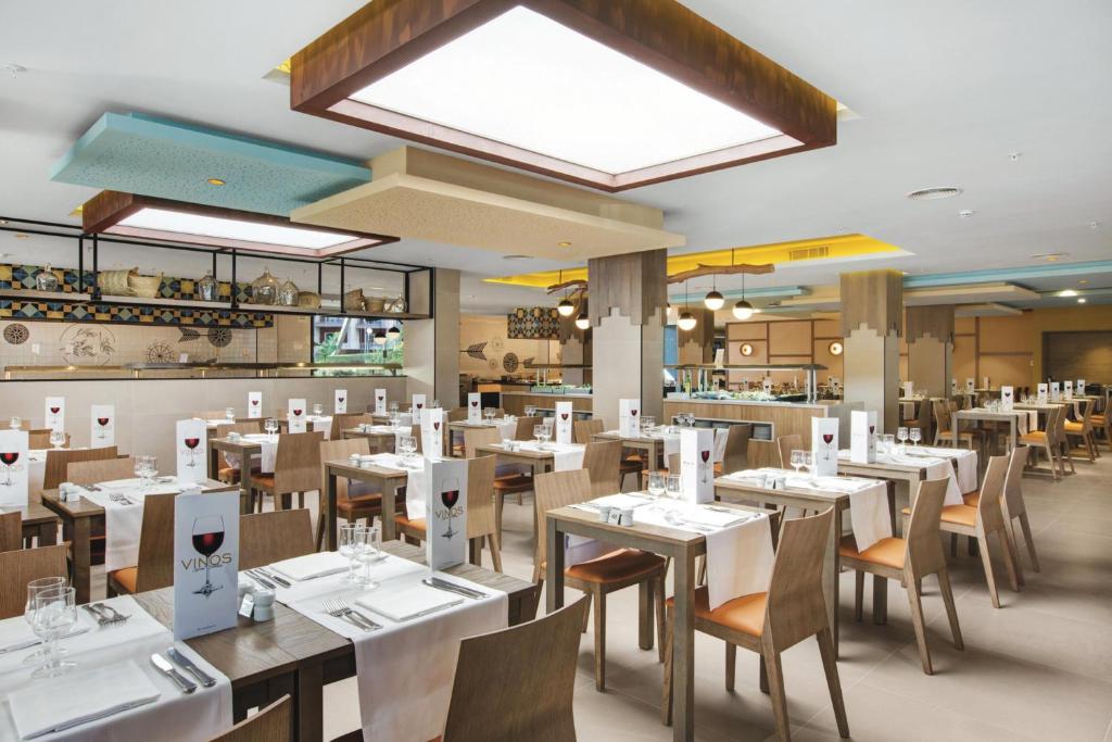 Moderns restorāns ar elegantiem galdiem un krēslām, kas rotāti ar baltām galdautām un ēdienkartēm, kas izceļ vīnus. Gaisma un interjers rada patīkamu atmosfēru.