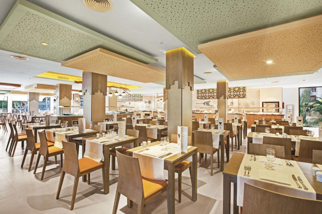 Moderns restorāns ar elegantiem koka galdiem un krēsliem, kas piedāvā patīkamu atmosfēru. Interjerā ir redzamas stilīgas gaismas un dekoratīvie elementi, radot mājīgu vidi ēšanas baudīšanai.