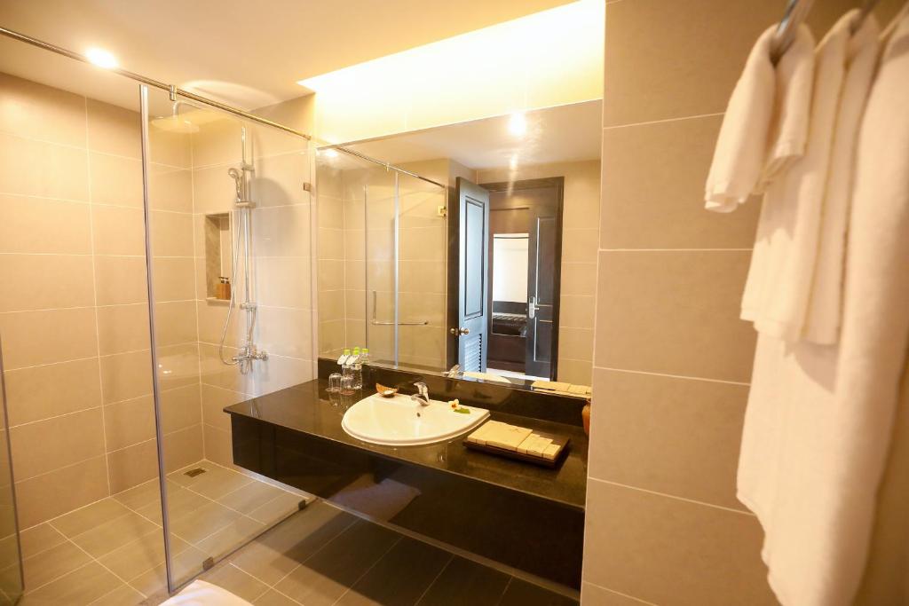 Mūsdienīgs un elegants vannas istabas interjers ar stikla dušu, melnu izlietni un plašu spoguli. Svaigi balti dvieļi un higiēnas piederumi pieejami uz galda.