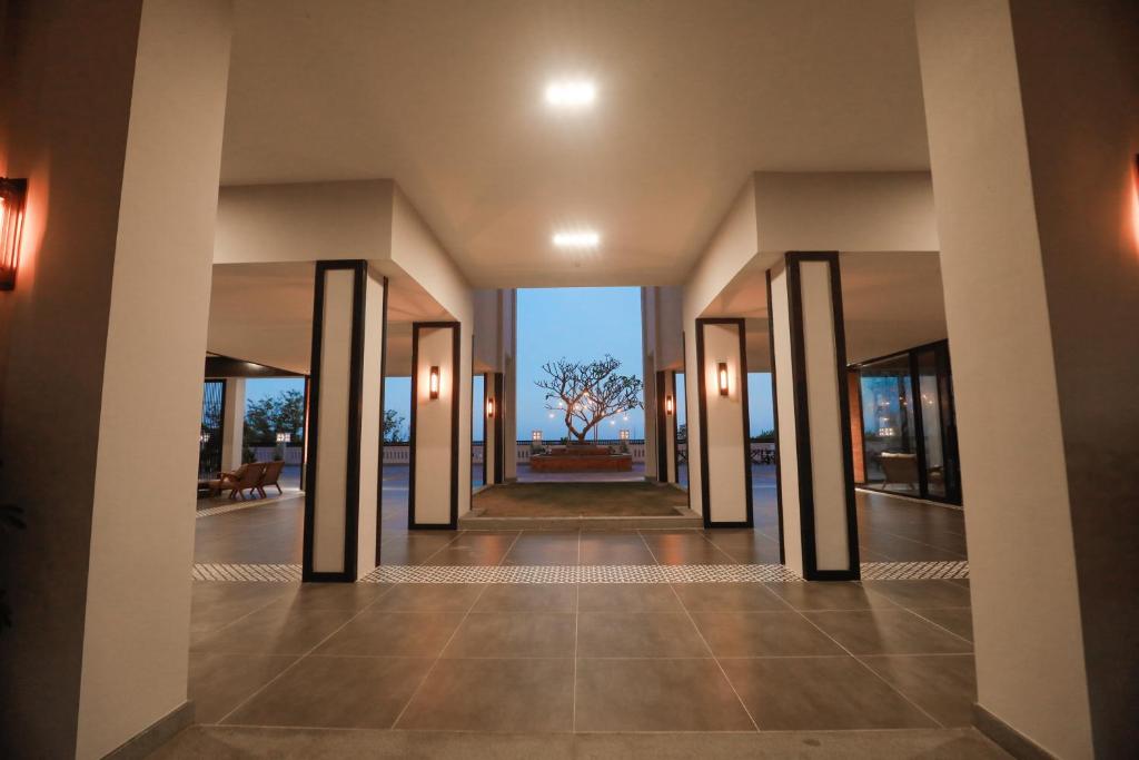 Mūsdienīga viesnīcas ieeja ar elegantiem arhitektūras elementiem un skatu uz dārzu. Apgaismojums radīs patīkamu atmosfēru un aicina atpūsties.