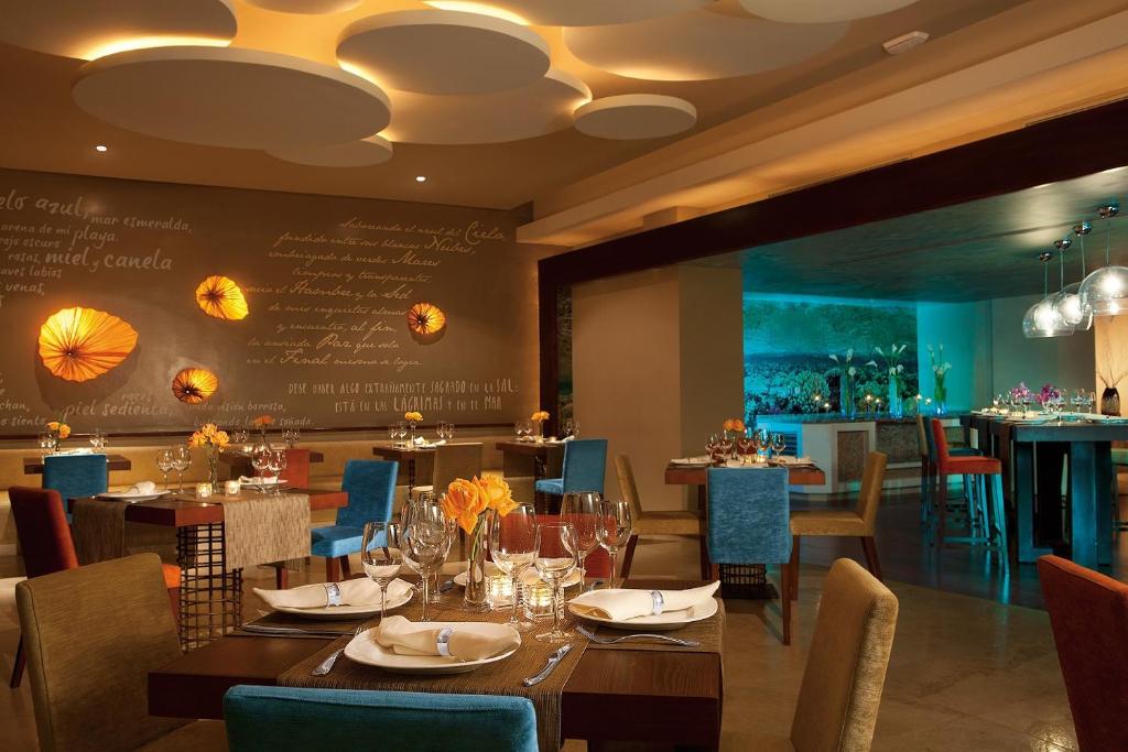 Elegants restorāns ar stilīgu interjeru, kas ietver krāsainus krēslus un romantisku apgaismojumu. Sienas rotā oriģinālas dekorācijas, radot patīkamu atmosfēru.