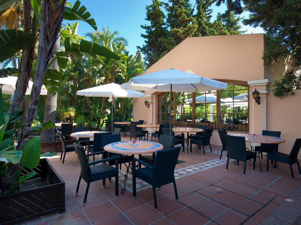 Ārtelpa ar galdiem un krēsliem, apzaļumota ar palmām un citiem augiem, kā arī jumtiem. Ideāla vieta relaksācijai un ēšanas baudīšanai.