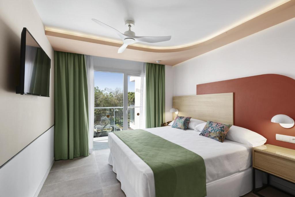 Mūsdienīga viesnīcas numura interjers ar divguļamo gultu, zaļām aizkariem un balkonu. Numurā ir televizors un gaišas krāsas sienas, radot patīkamu atmosfēru.