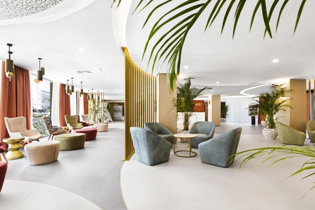 Mūsdienīgs viesnīcas vestibilis ar krāsainiem krēsliem un dīvāniem, apzaļumotām telpām un elegantu interjeru. Ideāla vieta atpūtai un socializēšanai.