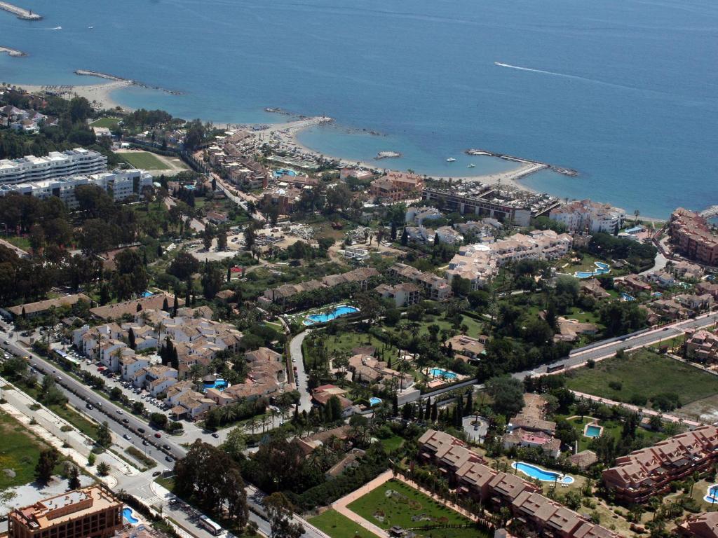 Kūrortpilsētas ainava ar piekrasti, peldbaseiniem un zaļām teritorijām. Skats uz jūru un viesnīcu kompleksiem.