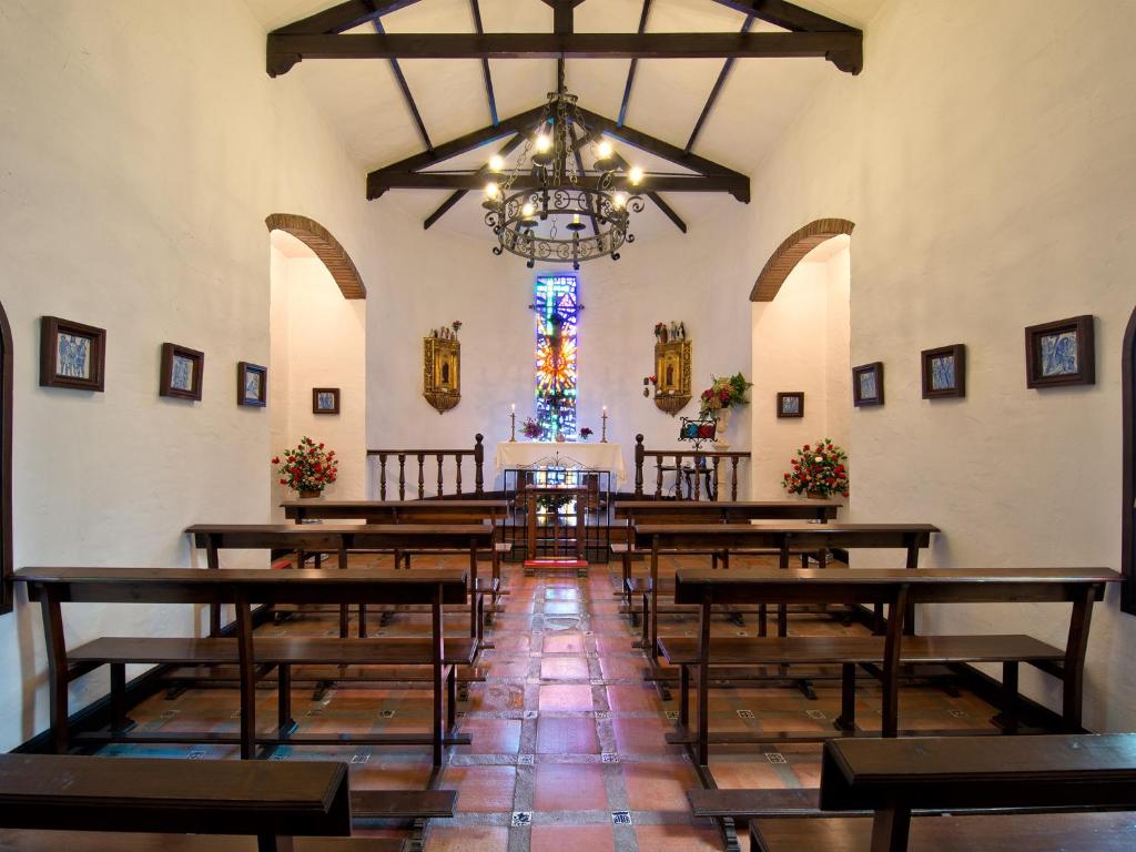 Koka soli un ziedu kompozīcijas rotā šo klusā, gaisīgā baznīcas interjeru, kurā ir krāsains vitrāžas logs un vienkārša altāra zona.