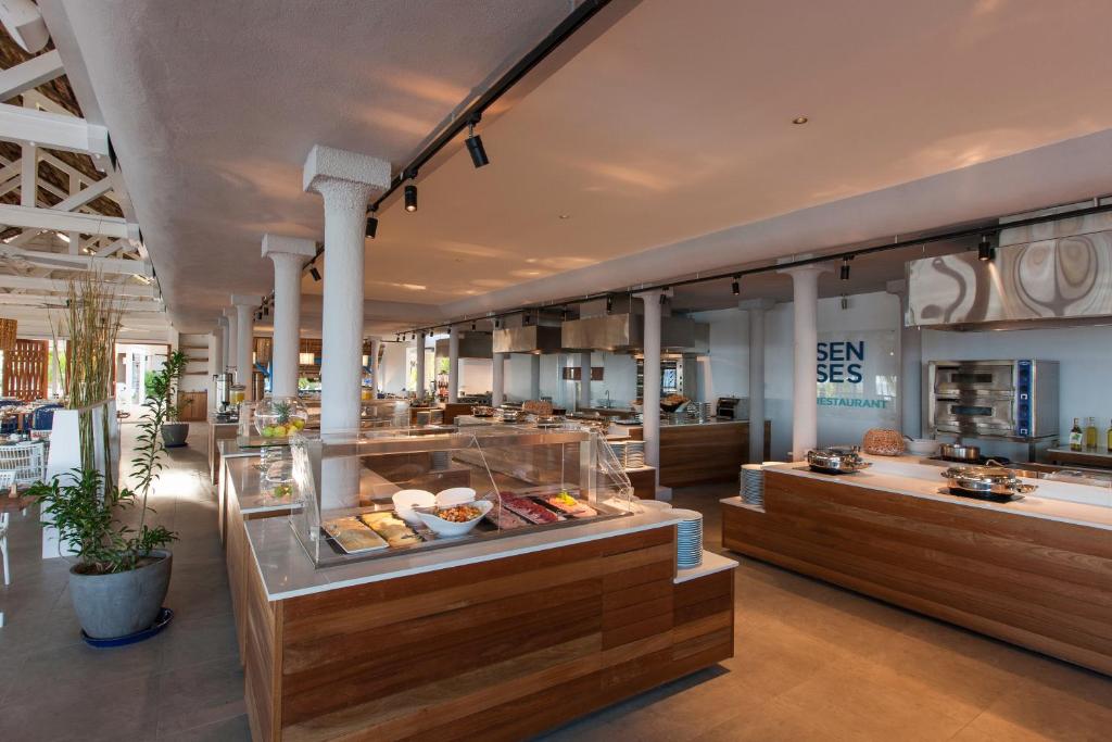 Mūsdienīgs restorāns ar atvērtu plānojumu, kas ietver koka un metāla elementus, piedāvā dažādus ēdienus bufetē. Gaismas un telpas dizains rada patīkamu atmosfēru.