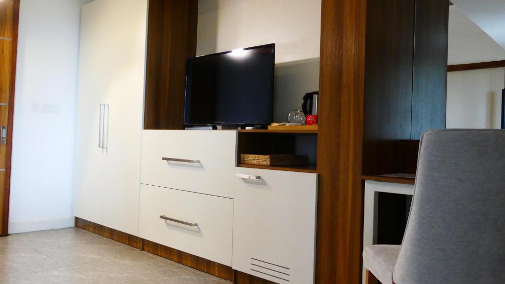 Mūsdienīgs viesnīcas numuriņš ar televizoru, gludu balto mēbeļu komplektu un koka akcentiem, piedāvājot komfortu un ērtības. Ideāla vide relaksācijai un atpūtai.