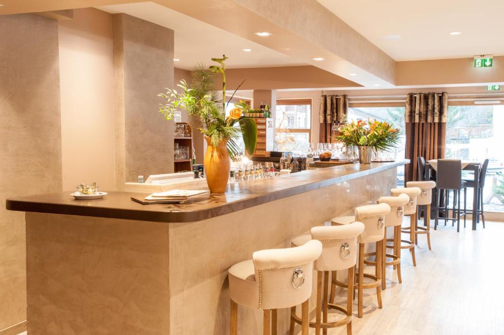 Mūsdienīgs bārs ar elegantu apdari, iekārtots ar koka letēm un ziedu kompozīcijām. Bāra krēsli ar elegantiem apdares elementiem piešķir vietai viesmīlīgu atmosfēru.