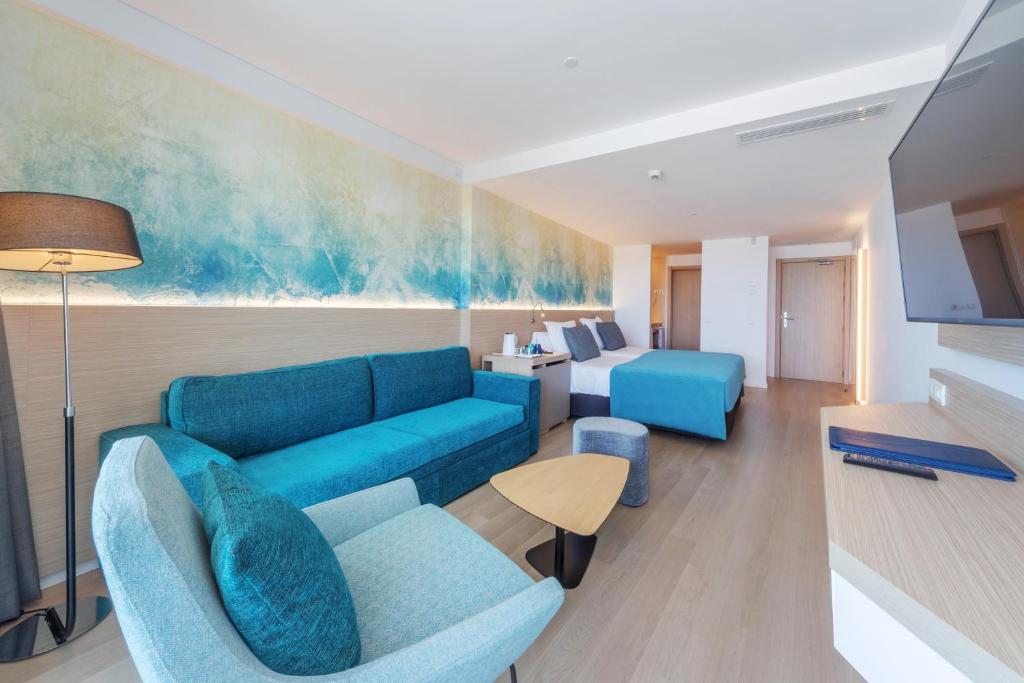 Mūsdienīgs viesnīcas numurs ar zilām un zaļām krāsām, ērtiem mēbeļiem un plašu telpu, kas rada relaksējošu atmosfēru.