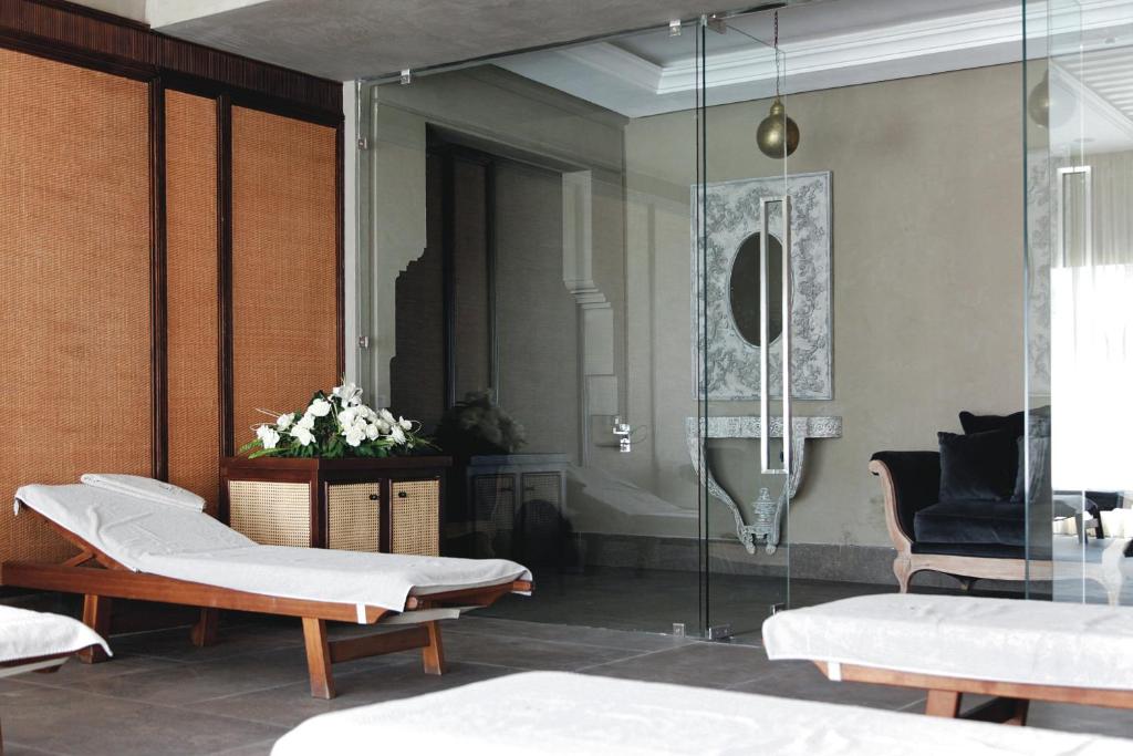 Mūsdienīgs spa interjers ar koka guļamkrēsliem, stikla sienām un elegantu dekoru, radot relaksējošu atmosfēru. Ziedu kompozīcija pie skapīša papildina telpas estētiku.