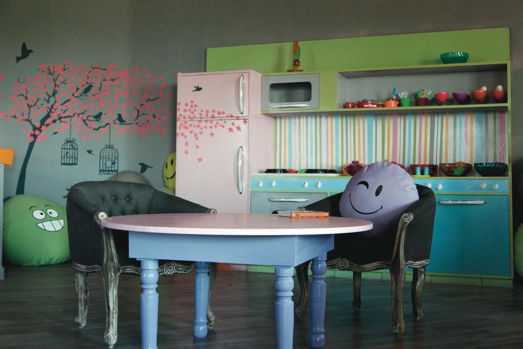 Krāsaina un jautra virtuve ar rozā ledusskapi un daudzkrāsainu galdu. Telpā ir divi krēsli un mīkstās rotaļlietas, kas piešķir viesmīlīgu atmosfēru.