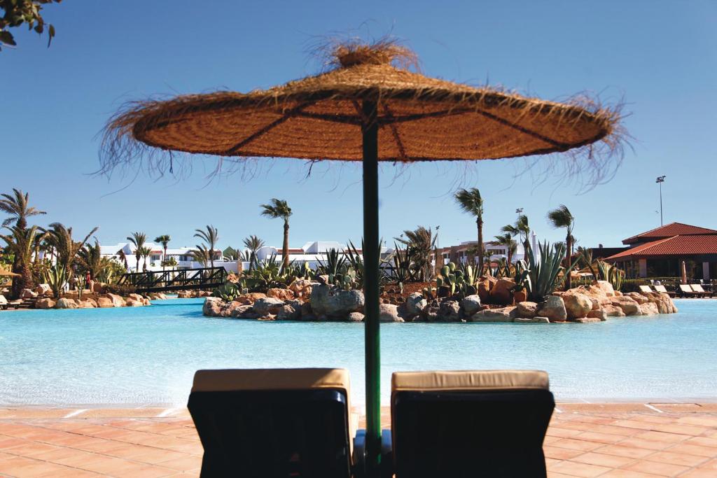 Tropu paradīze ar baseinu un sauļošanās krēsliem zem salmu jumta, kas piedāvā mierīgu atpūtu. Dabas elementi un palmām apkārt veido ideālu atpūtas vietu.