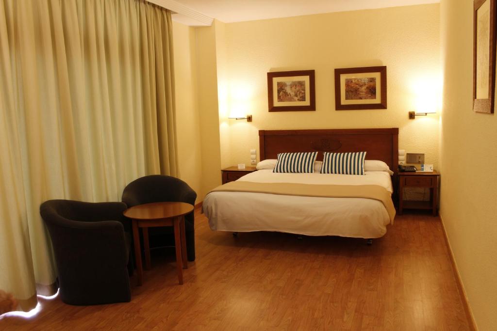 Mūsdienīga viesnīcas numura interjers ar divguļamo gultu, ērtu atpūtas zonu un dabiskiem apgaismojuma elementiem. Guļamistaba ir iekārtota ar siltām krāsām un elegantu dizainu.