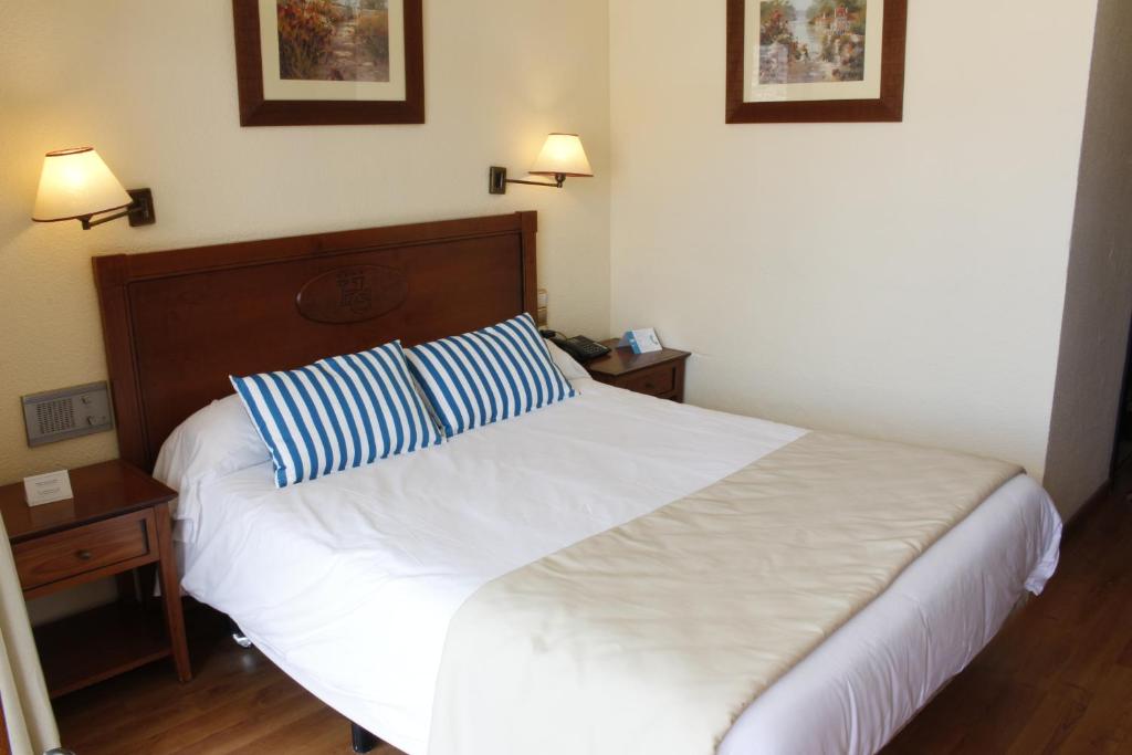 Mūsdienīgs viesnīcas numurs ar plašu gultu un svītrainām spilveniem, apgaismots ar siltām lampām. Interjerā ir koka mēbeles un mākslas darbi uz sienām.