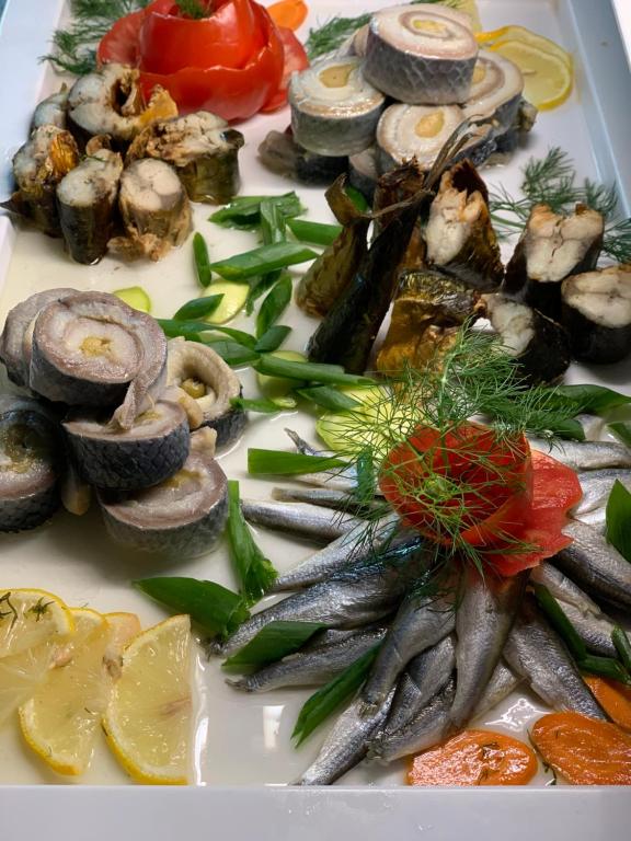 Svaigu jūras produktu uzkodu šķīvis ar dažādiem suši ruļļiem, anšoviem, tomātu rotājumiem un garnējumu no dilles un citrona šķēlēm.
