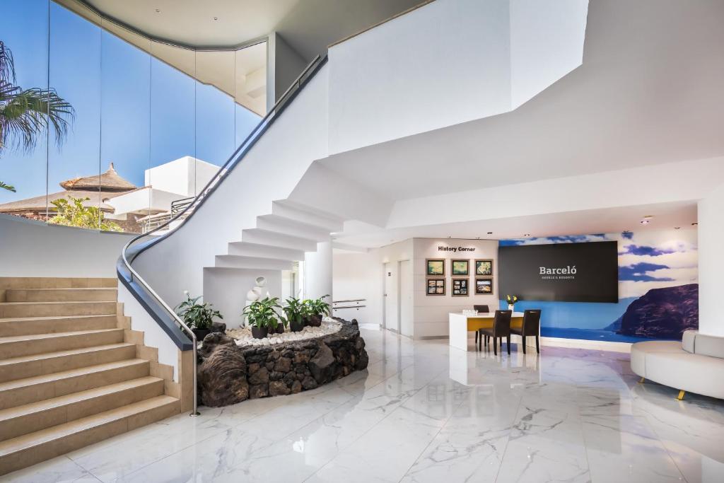 Mūsdienīgs viesnīcas interjers ar plašu ieeju, elegantām kāpnēm un viesmīlīgu reģistratūru. Gaismas un dabas elementi rada patīkamu atmosfēru.