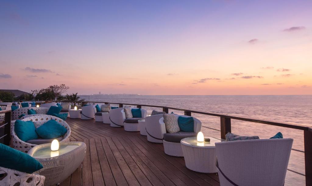 Moderns terases dizains ar baltām mēbelēm un ziliem spilveniem, kas piedāvā skatu uz saulrietu pie jūras. Ideāla vieta relaksācijai un atpūtai.