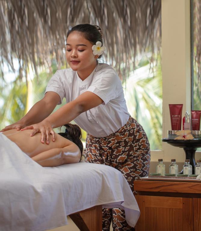 Masāžas sesija, kurā pieredzējusi masiere sniedz relaksējošu masāžu klientam, kamēr fonā redzami masāžas produkti un zaļojoša daba.