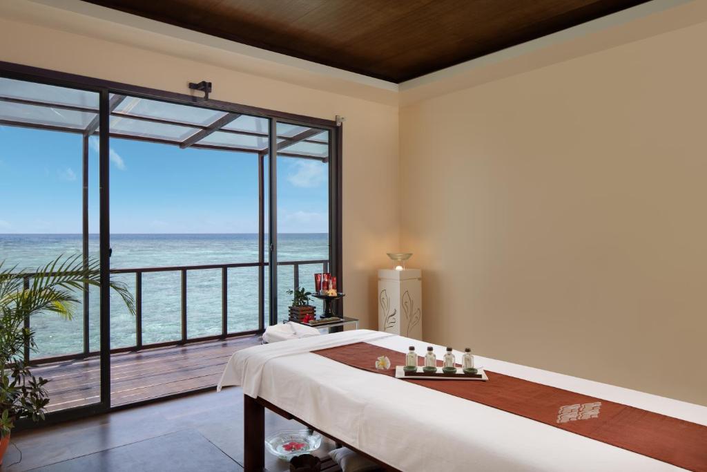 Relaksējoša masāžas telpa ar skatu uz okeānu, kurā ir masāžas galds un aromterapijas eļļas. Ideāla vide atpūtai un labsajūtai.