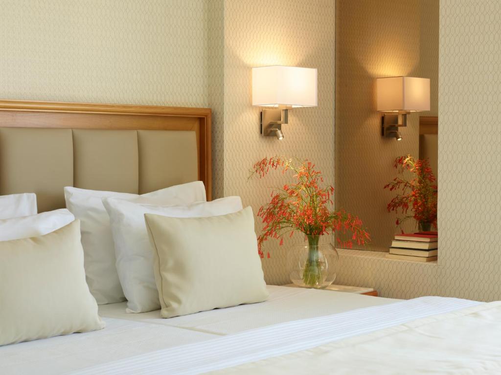 Mūsdienīgs guļamistabas interjers ar ērtām spilveniem, gaišu apgaismojumu un dekoratīvu ziedu kompozīciju. Eleganti un relaksējoši dizaina elementi rada patīkamu atmosfēru.