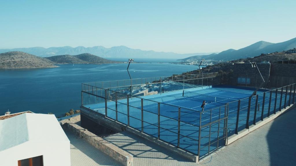 Tennis courts with a stunning sea view, surrounded by mountains and a clear blue sky. Perfect for outdoor sports enthusiasts.
