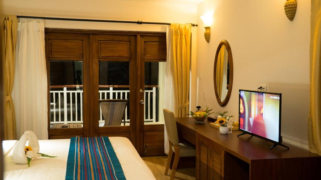 Moderns viesnīcas numurs ar koka durvīm, ērtu gultu un televizoru. Telpā ir gaismas un dabisks apgaismojums, kā arī dekoratīvs elements uz galda.