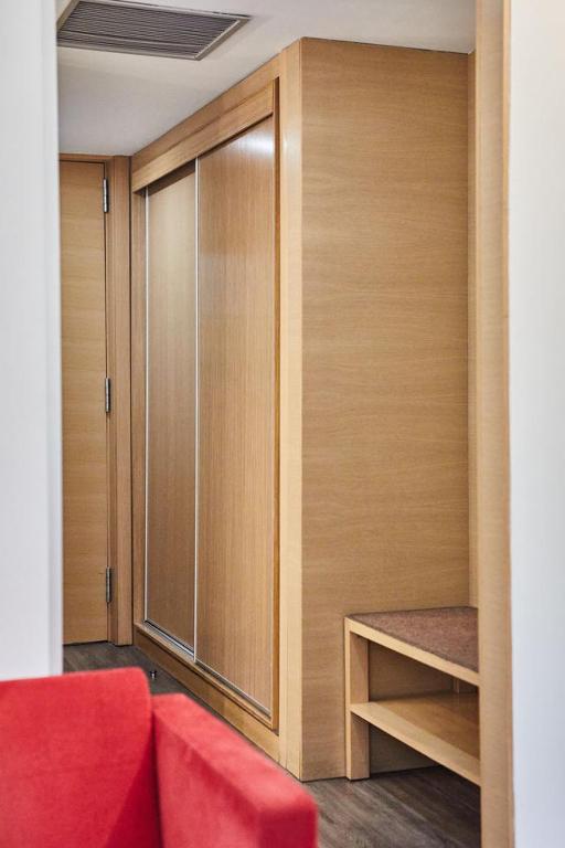 Mūsdienīga interjera attēls ar koka skapjiem un sēdvietu, kas piešķir siltumu un komfortu telpai. Ideāls risinājums lietošanai viesnīcās vai mājās.