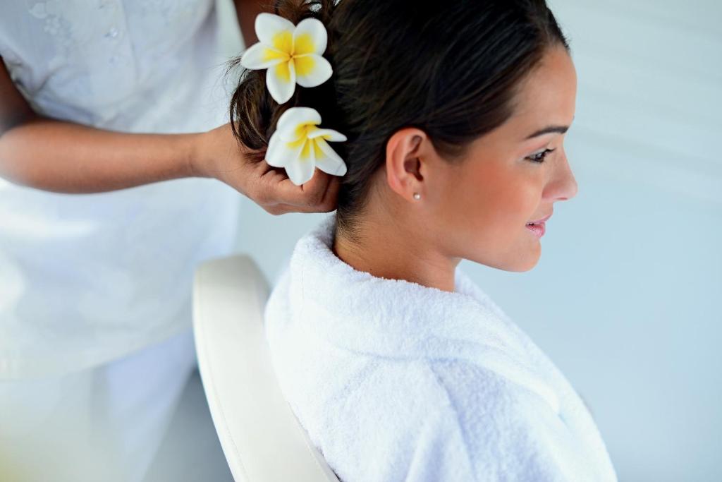 Sieviete ar ziediem matos saņem frizūru spa vai skaistumkopšanas salonā, izskatoties mierīgi un relaksēti.