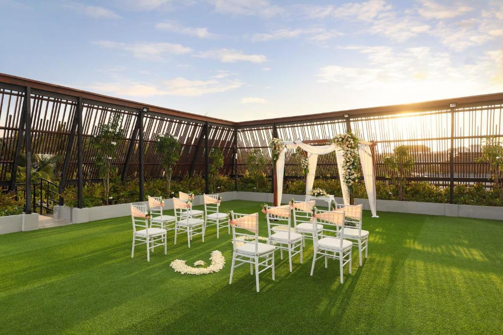 Romantiska kāzu ceremonijas vieta uz jumta ar zālienu, kurā ir sēdvietas un dekorēta ar ziediem.