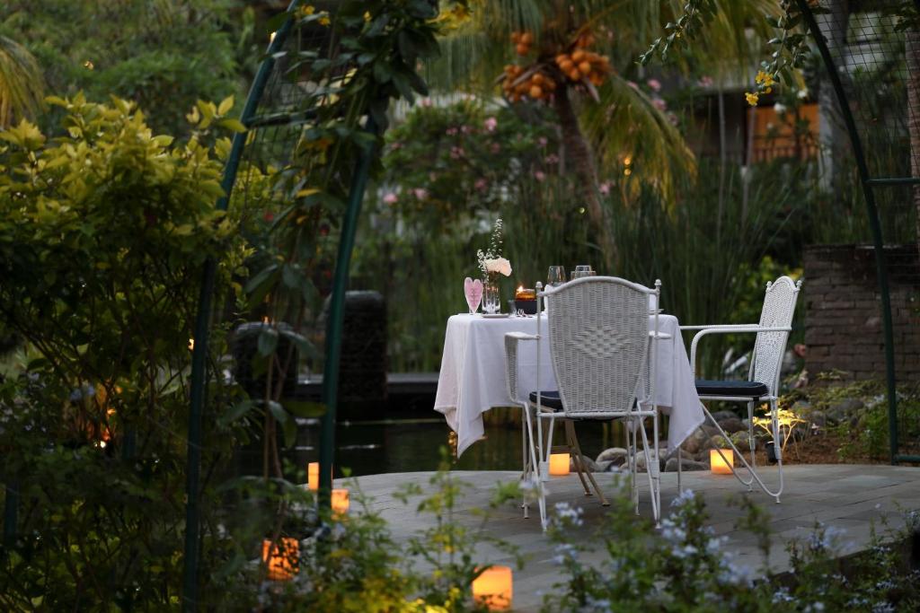 Romantisks galdiņš diviem dārzā ar ziediem, svecēm un skaistu apgaismojumu. Ideāla vieta, lai izbaudītu vakariņas brīvā dabā.