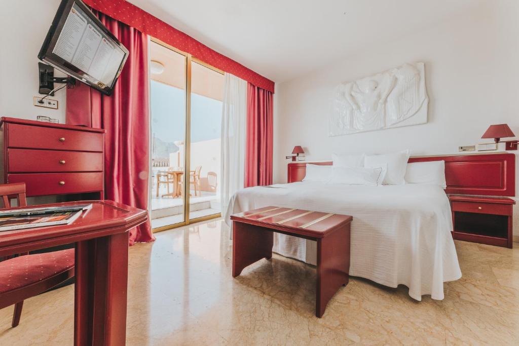 Mūsdienīgs viesnīcas numurs ar sarkanu interjeru, plašu gultu un terasi. Numurā ir televizors, kumode un ērta sēdvieta.