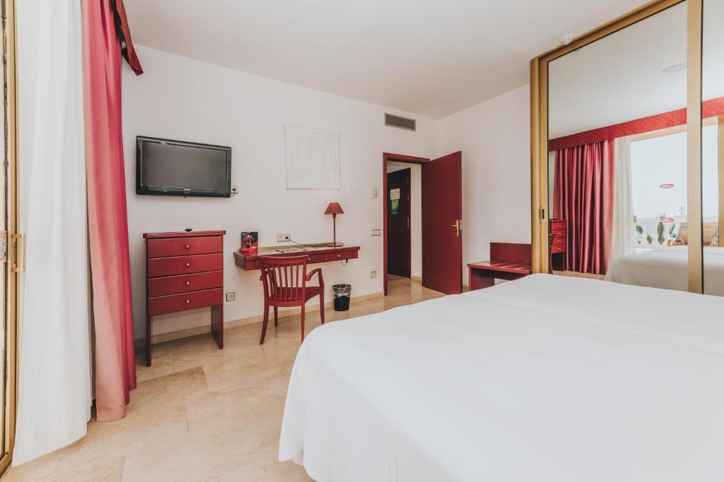 Mūsdienīgs viesnīcas numurs ar divām gultām, rakstāmgaldu un televizoru, kas piedāvā gaišu un ērtu atmosfēru. Apskatāma arī atvērta skata daļa ar logiem un sarkanu aizkaru.