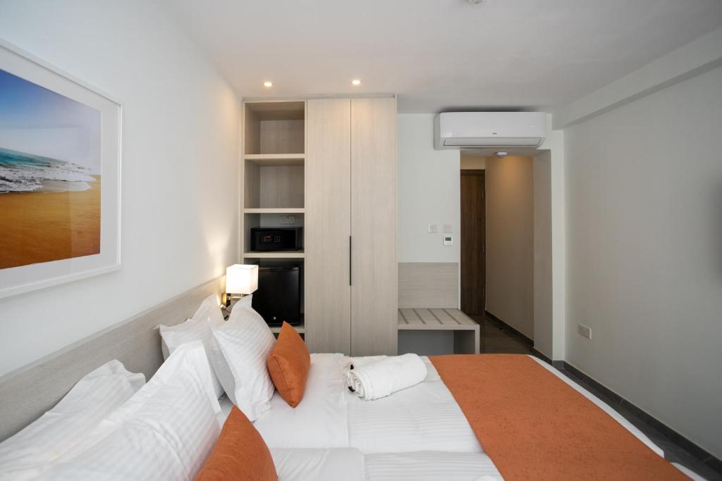 Mūsdienīga viesnīcas istaba ar divguļamo gultu, apgaismojumu un modernu interjeru. Redzami sienas skapis un neliels galdiņš, kas piedāvā ērtības viesiem.