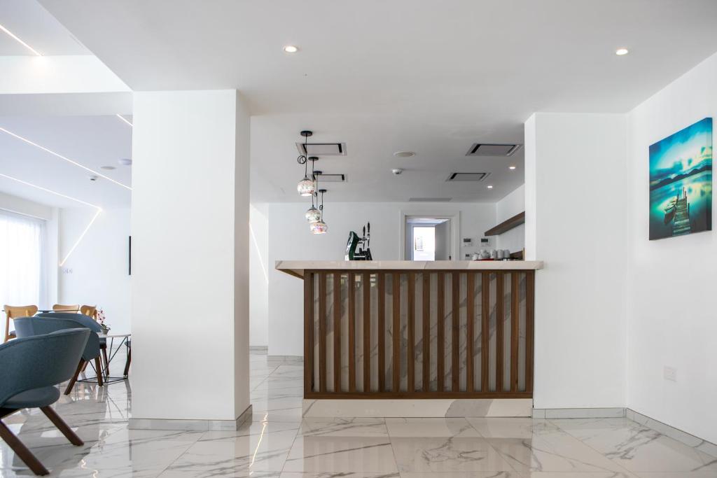 Mūsdienīga viesnīcas recepcija ar elegantām mēbelēm un gaišu interjeru. Uz galda atrodas kafijas automāts un dekoratīvi elementi, kas veido patīkamu atmosfēru.