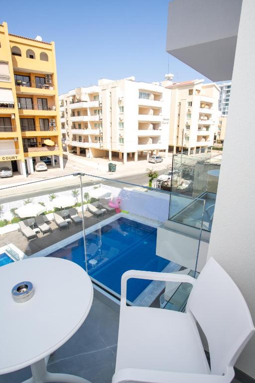 Balcony view overlooking a swimming pool and surrounding buildings, featuring a small table and chair.