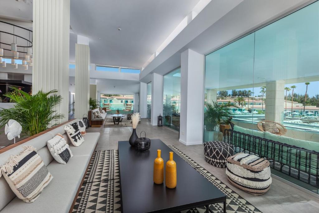 Mūsdienīgs interjers ar plašām stikla sienām, atpūtas zonām, dekoratīviem elementiem un augiem, kas rada gaisīgu un elegantu atmosfēru.