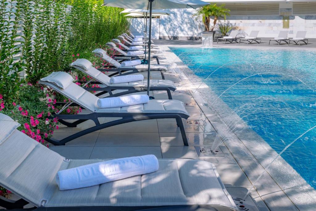 Mūsdienīgs peldbaseins ar saulessargiem un atpūtas krēsliem, apstādīts ar ziediem un zaļumiem. Ūdens strūklakas pievieno relaksējošu atmosfēru.