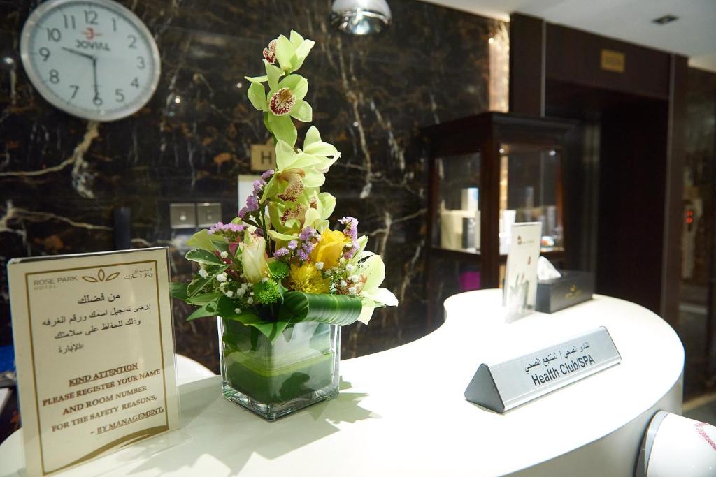 Rose Park Hotel Al Barsha reģistratūras lete ar ziedu kompozīciju.