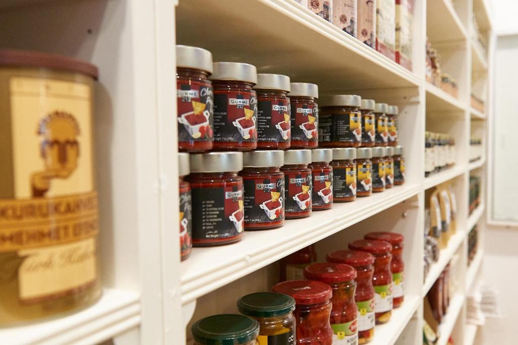 Kārtīgi sakārtoti burciņi plauktā Rose Park Hotel Al Barsha veikalā.